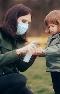 shutterstock_european mother spraying sanitizer on child